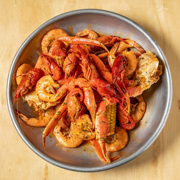 A metal platter filled with Granchio's seafood boil, including crawfish, shrimp, crab legs, and corn.