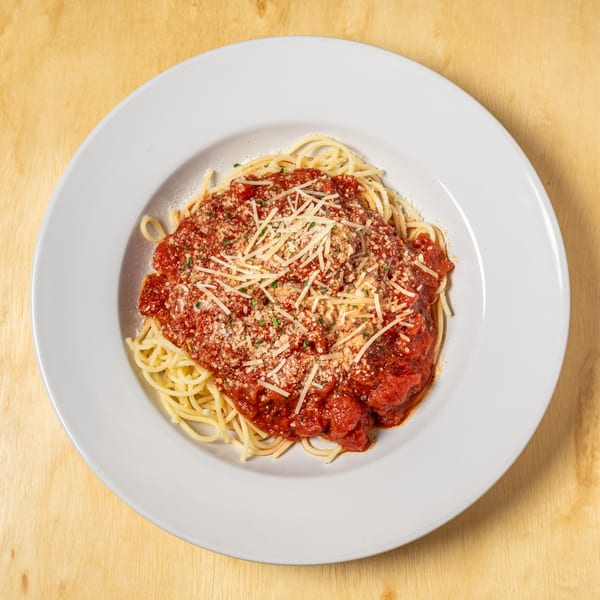 Spaghetti with red sauce, meatballs, and grated cheese on a white plate at Granchio Seafood & Pasta.